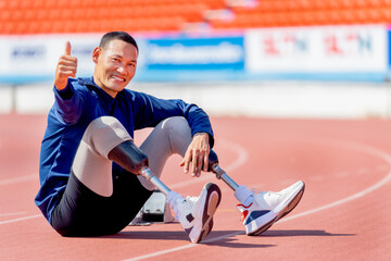 Sport man athlete with a prosthesis on his leg sit on the track and show thumbs up after exercise...