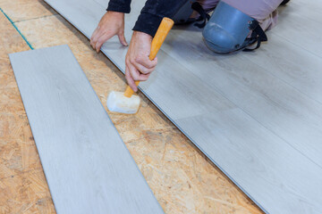 In newly constructed house worker is installing vinyl laminate flooring