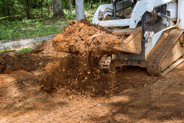Fototapeta na wymiar Mini bulldozer is used to work with earth, move soil, improve landscaping of territory
