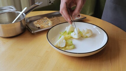 The male chef makes the composition of the dish for serving. The cook prepares a dish with fish. Close-up professional chef in the restaurant kitchen serving a dish adding the last ingredient