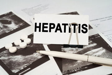 On the ultrasound pictures there is a pen and a business card with the inscription - Hepatitis
