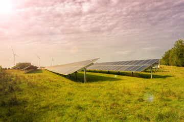 Many solar panels and wind generators installed in Germany on a field in the countryside where...