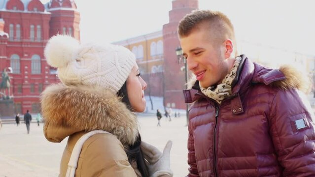 Young man and woman talk and smile near Kremlin complex 