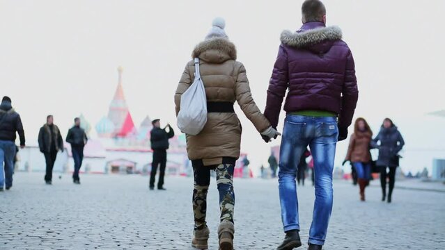man and woman walk by Red Square near Spasskaya Tower