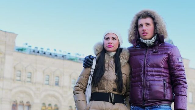 couple talk and look around near edifice of GUM at Red square