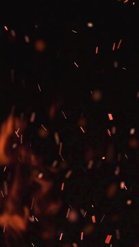 ultra slow motion high speed shot of fire flames and glowing ash particles on black background - vertical video for reel and story