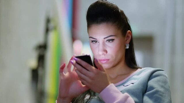 woman uses smart phone which she hold in her hands near face