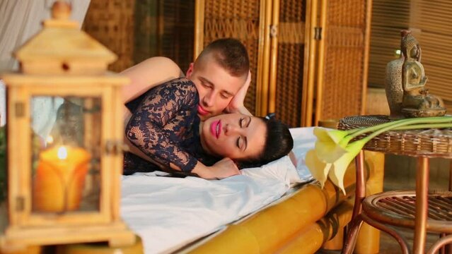 flower on table with buddha statuette near bed with couple talk