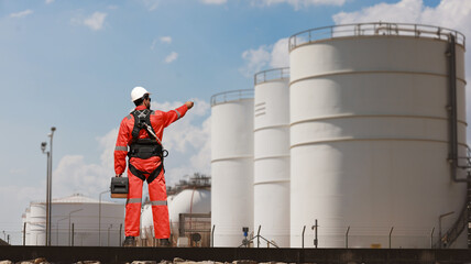 Engineer with orange safety uniform and safety harness work at site line of factory