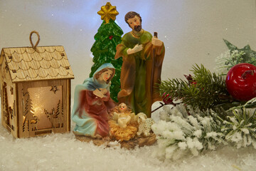 Christmas scene of the Nativity of Jesus, Nativity of Christ, Nativity scene Statuettes decorated in the snow with a fir branch