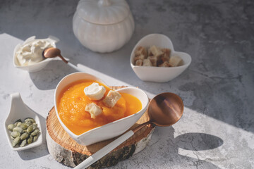 Pureed pumpkin soup with sesame seeds and pumpkin seeds in a heart-shaped plate. All-season vegan...