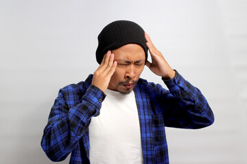 Young Asian man is in need of painkillers as he is suffering from painful feelings migraine...