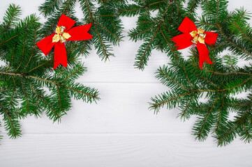 Fototapeta na wymiar Christmas background with green tree branches on wood and red bows