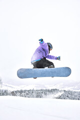 Vertical shot of the freeride snowboarder that is jumping with a board and scattering white snow...