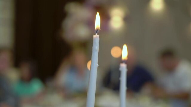 A close up of a two burning white candles. Decoration at the reception venue. Party in a restaurant. Holiday.