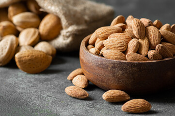 Delicious sweet almonds in wooden bowl on rustic background, roasted almond nut, healthy food