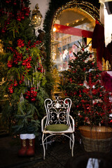 Christmas tree with xmas decorations and white metal chair with green velvet pillow