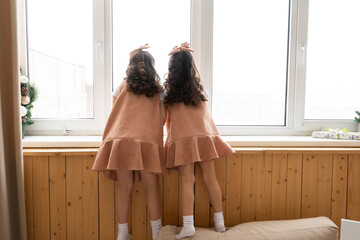 Two little girls waiting for Santa on the windowsill. Christmas holiday together