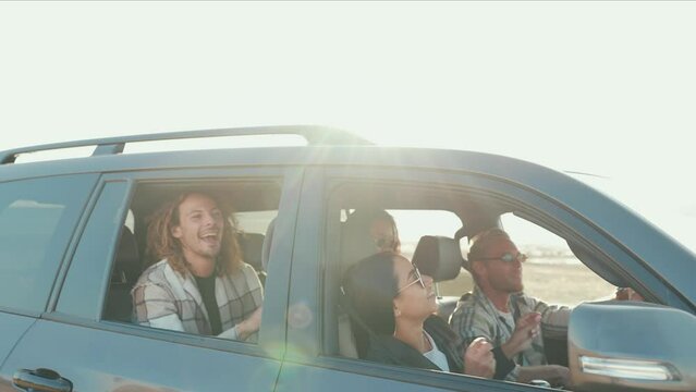 Cheerful multinational friends singing and riding in car in summertime