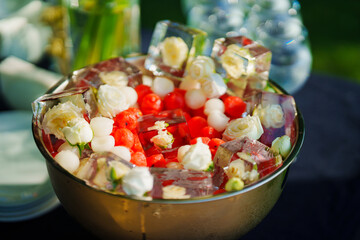 A bowl of ice cubes with frozen flowers and berries. 