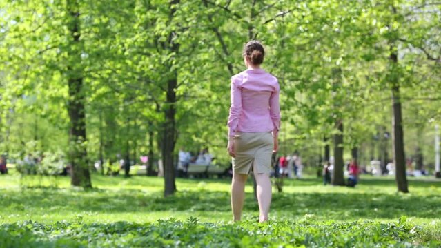 Beautiful barefoot woman walk in park in spring sunny day