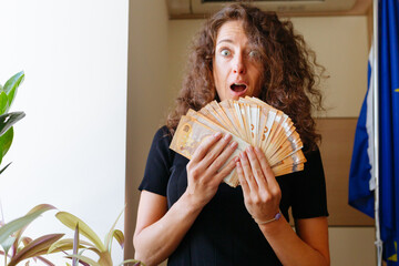 surprised woman watching at the money she is holding in both hands