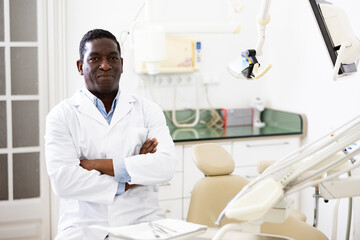 Confident qualified african american dentist posing in modern dental clinic office, looking at camera with smile ..