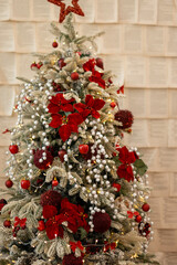 Christmas tree with lights glowing and red flowers, copy space. 