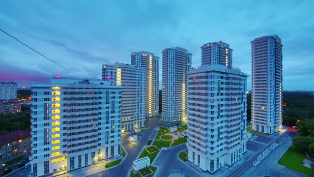 Housing estate stands near trees against blue sky, time lapse 