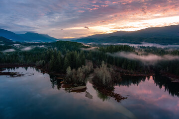 Fototapeta na wymiar Valley by Lake, Mountains and Green Trees covered in fog. Canadian Landscape Nature Aerial Background