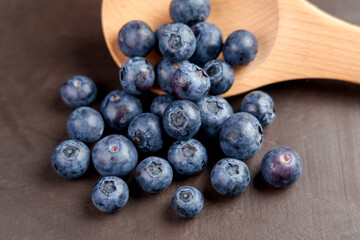 Fresh cultivated harvested blueberry fruits in a wooden spoon. Blue berry crop.