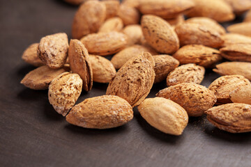 Wooden bowl with delicious roasted almond nuts with nutshell. Christmas or New Year treats
