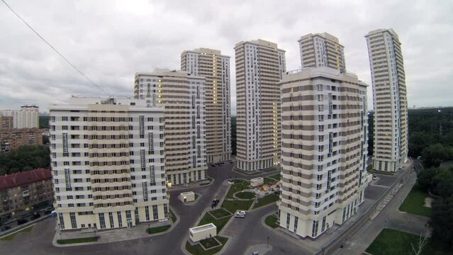 Housing estate stands near trees against cloudy sky at evening