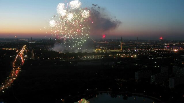 Fireworks flashes and sparks above city with pond and traffic