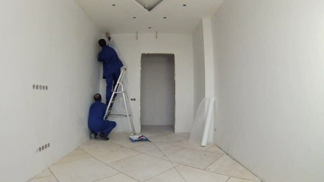 Two workers prepare to wall spackling, photographer photographing