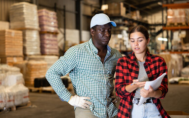 African American salesman helping young customer choose materials at storage warehouse