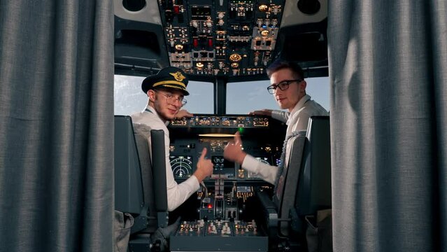 Portrait of serious young airplane pilot captains in uniform preparing for flight in flight simulator cockpit