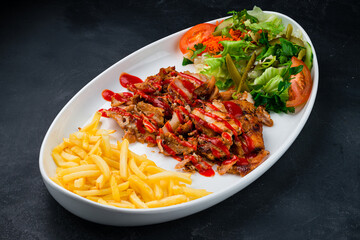 Shawarma meat with french fries and a salad of pickled cucumbers, tomatoes, carrots, lettuce, parsley and ketchup.