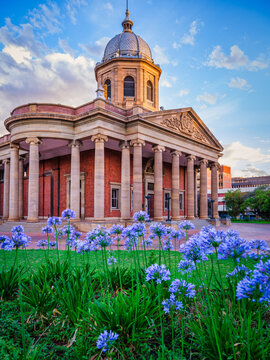 Vertical shot of the Fourth Raadsaal historic building with garden and flowers during sunset, Free State, Bloemfontein, South Africa