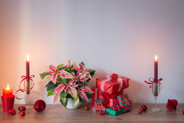 pink poinsettia with christmas red  decor on wooden shelf on background gray wall