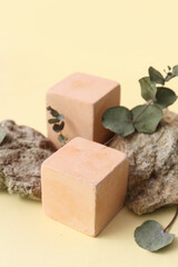 Decorative stone podiums with eucalyptus on beige background