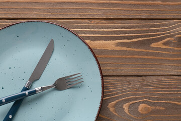 Silver fork with knife and plate on wooden table