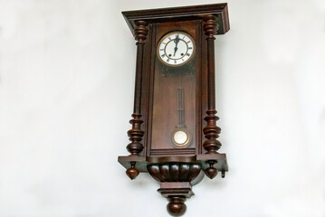 old wall clock with Roman numbers of hours on a white background, with a pendulum