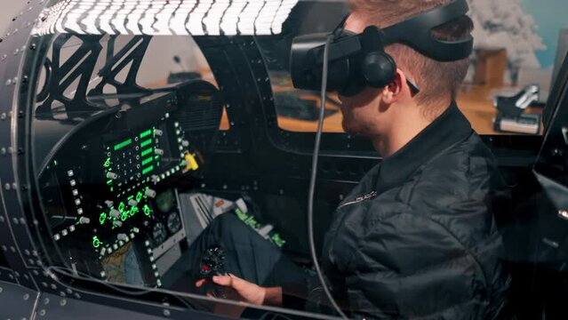 guy sitting in flight simulator of military plane wearing virtual reality glasses during flight entertainment