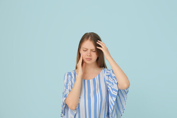 Young woman suffering from toothache on blue background