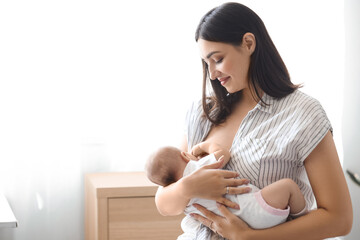 Young woman breastfeeding her baby at home - obrazy, fototapety, plakaty