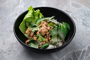 Salad Laap Gai minced chicken, rice, onion, lettuce, cilantro, chili and mint in a bowl.