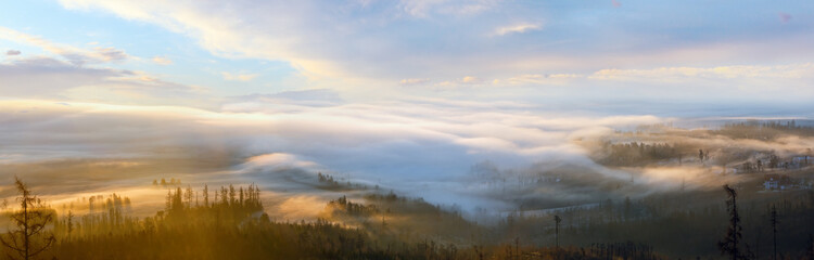 Clouds illuminated by the morning sun floating low over the valley. Country panorama.