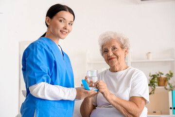 Senior woman with nurse taking pills in bedroom - obrazy, fototapety, plakaty