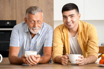 Senior man with his son drinking tea in kitchen